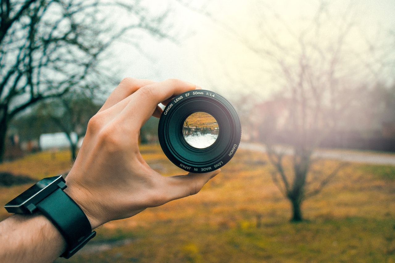 Photographer holding a camera lens toward a sunlit landscape