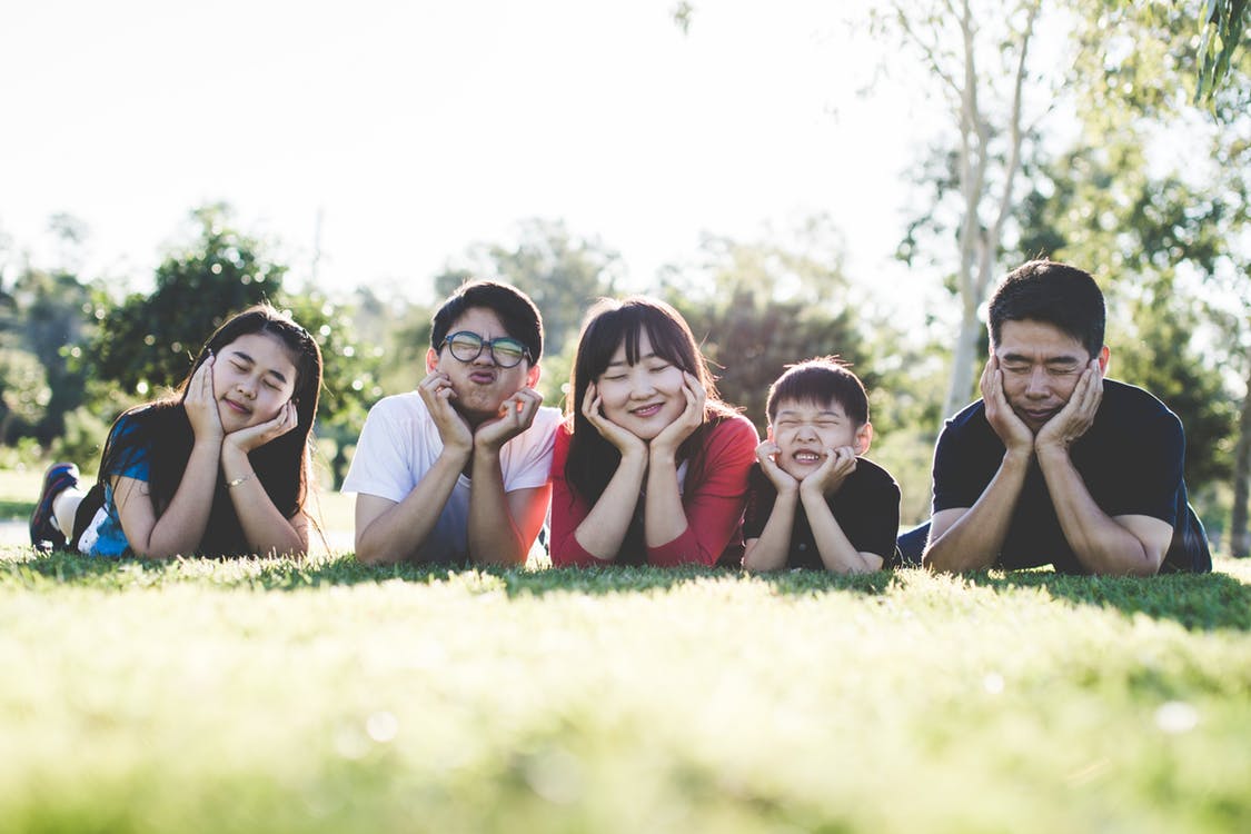 Family lying together on grass and making playful expressions for the camera