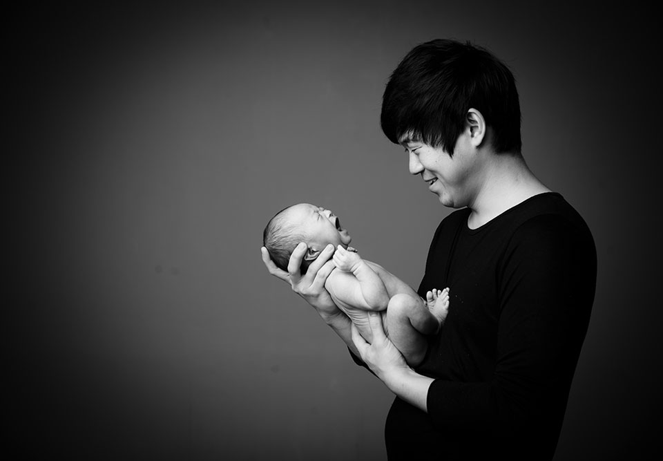 father smiling baby crying